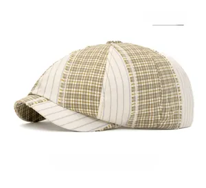 Detail of beige newsboy cap featuring patchwork plaid pattern and frayed brim edge