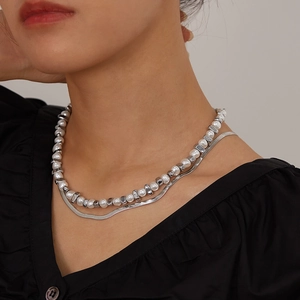 Close-up of double layer necklace featuring pearls and silver snake chain on model