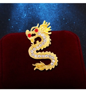 Détail de la broche dragon doré avec cristaux et pierre rouge sur velours rouge élégant