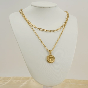 Detail of double-layer gold necklace with paperclip chain and round letter F pendant
