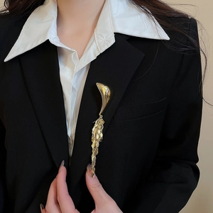 Macro view of a golden metallic fringe brooch pinned to a black blazer lapel