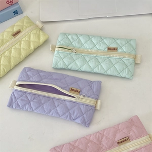 Quilted pastel pencil cases in yellow green purple and pink colors on a white desk