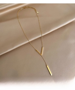 Detail of gold-plated V-shaped Y-necklace with long bar pendant on silk background