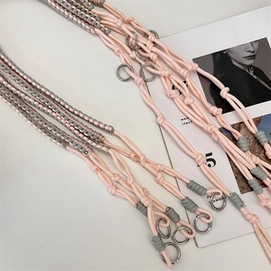 Detail of hand-woven pink and gray crossbody strap with silver metal ring buckle
