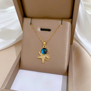 Elegant gold titanium astronaut necklace with sparkling blue helmet in a beige jewelry box