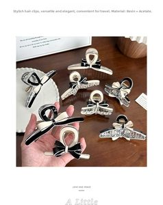 Detail of elegant acetate bow hair claw clip in cream and black on wooden surface