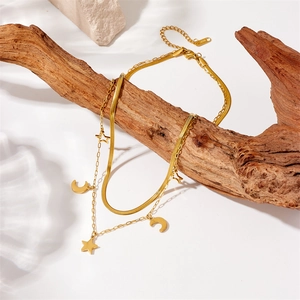 Detail of gold-plated stainless steel layered necklace with star and moon charms on wood