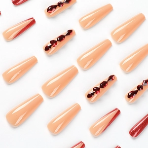 Long coffin fake nails with red glitter and rhinestones on nude base for a luxury look