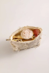 Detail view of beige linen toiletry bag showing fringe edges and interior storage capacity