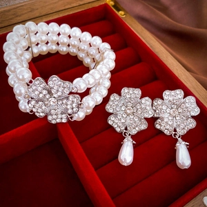 Close-up of triple-layer pearl bracelet and flower crystal earrings in a gift box