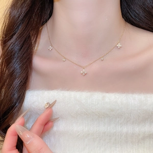 Detailed close-up of a gold-plated flower clover necklace with zircons and pearls on neck
