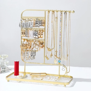Macro view of gold metal jewelry stand with necklace hooks and earring storage tray