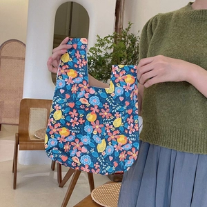 Floral cotton wrist bag with lemon and strawberry pattern held by a model