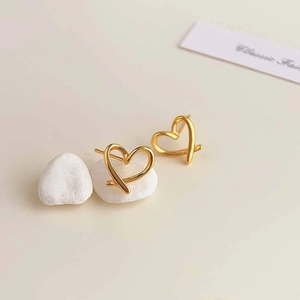 Detailed macro view of minimalist hollow heart-shaped 18K gold plated stud earrings