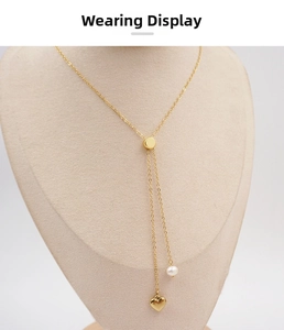 Detail of gold Y-shaped tassel necklace with pearl and heart pendant on display stand
