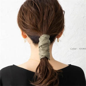 Detail of khaki green fabric hair tie wrapped around a low ponytail for retro styling