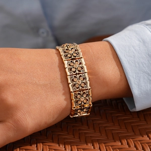 Detail of a vintage gold hollow flower bracelet with brown zircon stones worn on wrist