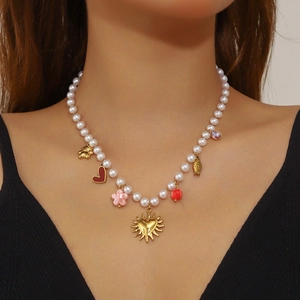 Collana di perle dorata con ciondoli a cuore, ciliegia e tondi indossata da una modella