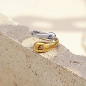 Detailed close-up of a two-tone teardrop open ring in gold and silver on a stone surface