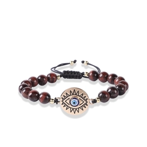 Close-up of natural stone beads with golden evil eye charm and adjustable braided cord