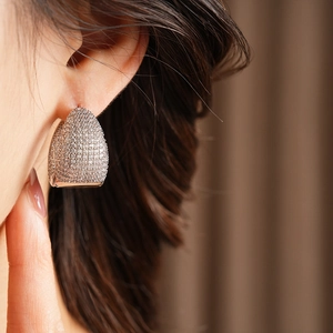 Close-up of rose gold C-shaped earrings with micro-paved sparkling cubic zirconia stones