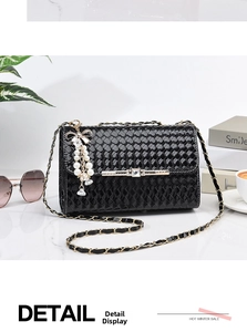 Close-up of black woven leather texture and gold buckle with crystal bow tassel