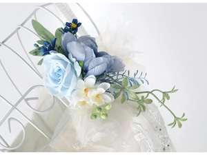 Detailed close-up of blue and white silk roses with pearls and lace on a bridal dress