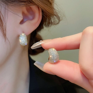 Macro shot of gold-plated C-shaped earrings with micro-pave crystals for a luxury shine