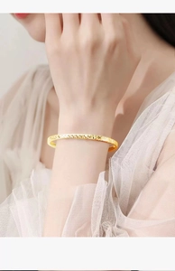 Detailed macro view of the gold-tone bangle showing sparkling texture on model's wrist
