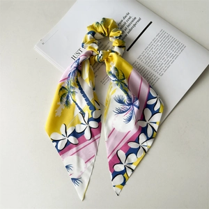 Detail of silk-like yellow and pink floral hair scrunchie with tropical coconut palm pattern