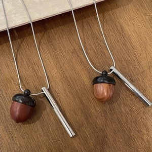 Minimalist wooden acorn pendant necklace with a sleek silver metal cylinder and snake chain