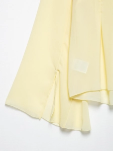 Detail view of light yellow chiffon fabric showing side slit and smooth airy texture