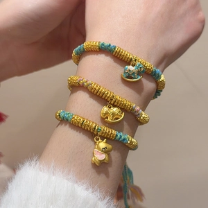 Detailed view of woven red strings with gold horse pendants and enamel animal charms