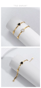 Close-up of golden heart pendant bracelets with black and white shells on snake chain