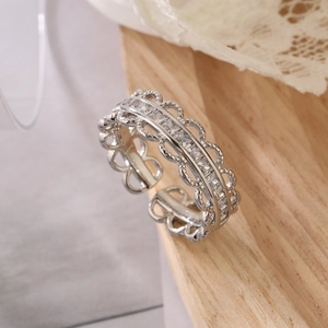 Detailed close-up of a silver lace hollow ring with zircon stones on a wooden background