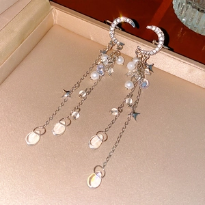 Detail of silver moon tassel earrings with pearls and stars in a jewelry box