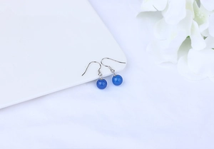 Detail view of blue agate drop earrings with silver hooks on a white minimalist plate
