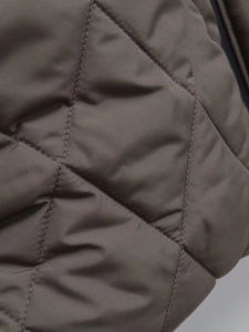 Detailed macro view of high-quality diamond-quilted stitching on a brown long cotton coat