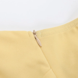 Detailed macro view of the invisible zipper and fine stitching on the yellow dress