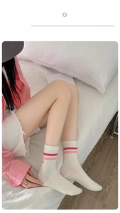 Detail of off-white crew socks featuring pink stripes and mini embroidery on cotton fabric