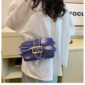 Detail of blue-purple snake skin shoulder bag with pearl accents and gold chain strap