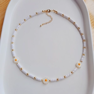 Detail of white heishi bead daisy necklace with golden spacers and adjustable lobster clasp