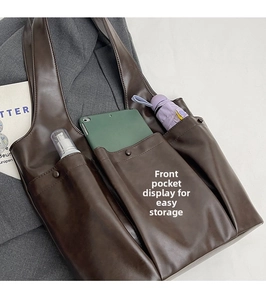 Detail showing deep brown leather tote bag with three functional front pockets for storage
