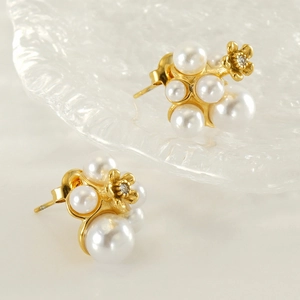 Detailed view of gold flower stud earrings with white pearls and zircon accents