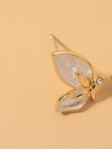 Macro detail of butterfly stud earring featuring white enamel and a sparkling zircon stone