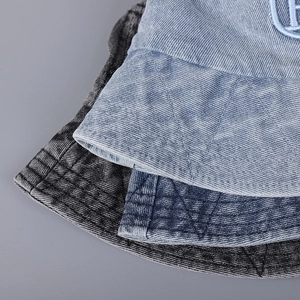 Détail de bobs en denim délavé avec broderie FF et surpiqûres de précision