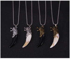 Detail of wolf head pendants in silver and bronze finishes with varied tooth colors