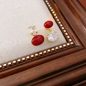 Dettaglio di orecchini ovali vintage placcati in oro con gemme rosse e zirconi bianchi