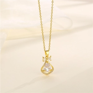 Golden teardrop zircon necklace with bow detail on a soft fabric background