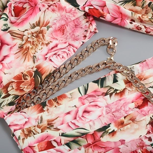 Detail of pink floral dress featuring elegant gold metal chain shoulder strap and rose print